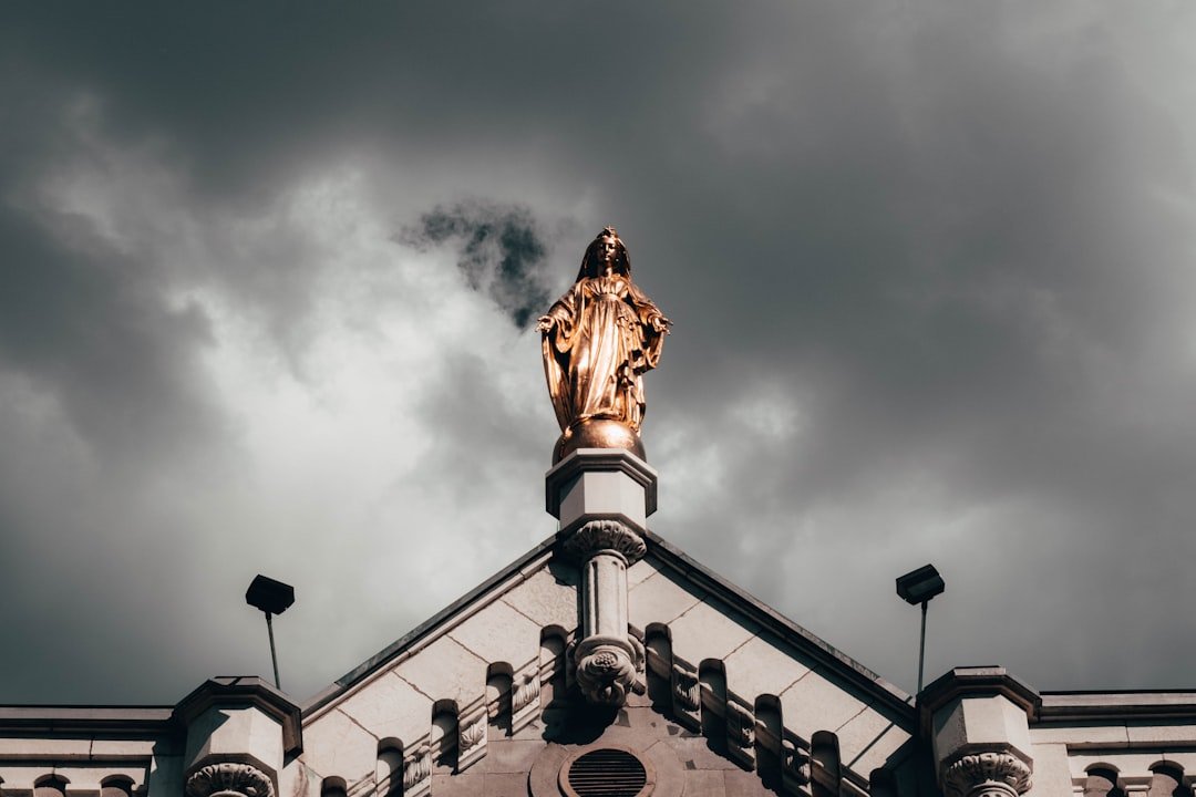 brown man in robe statue on top of building