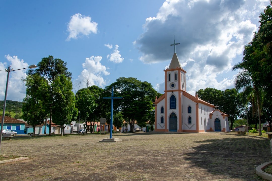 a church with a clock tower in the middle of a field