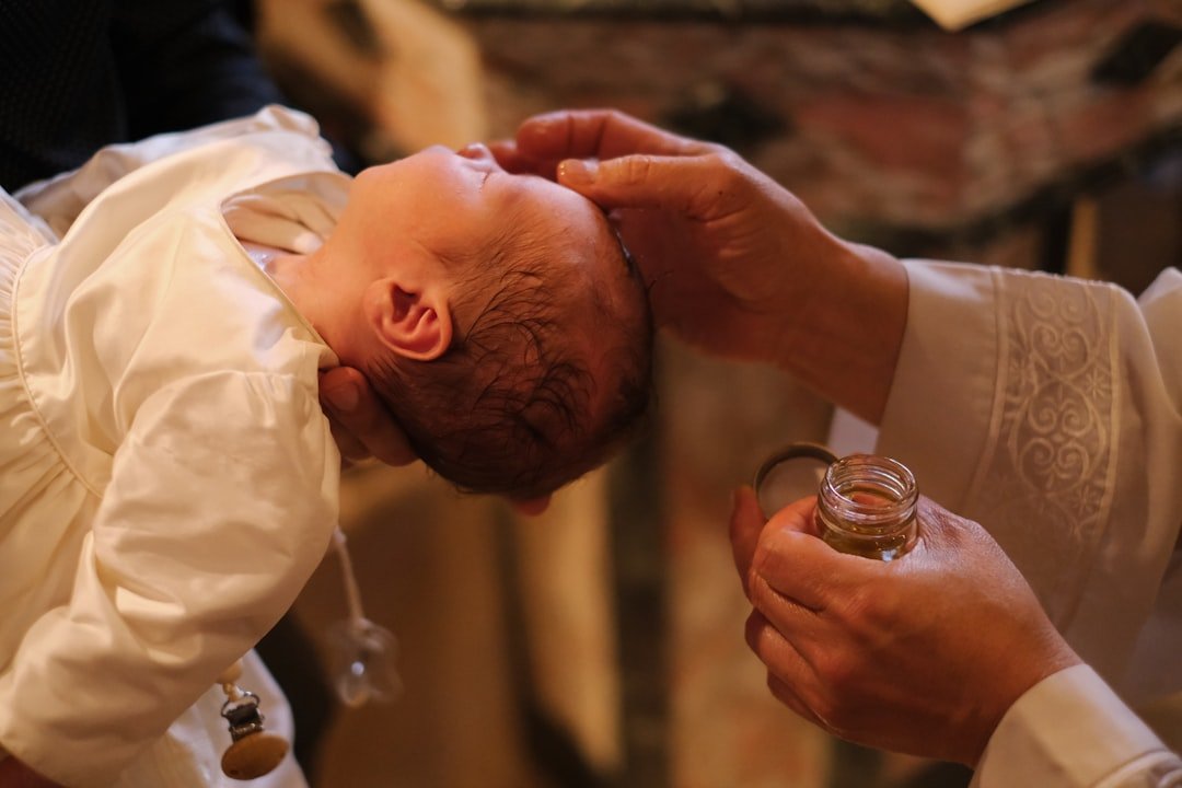 A baby being fed a glass of wine